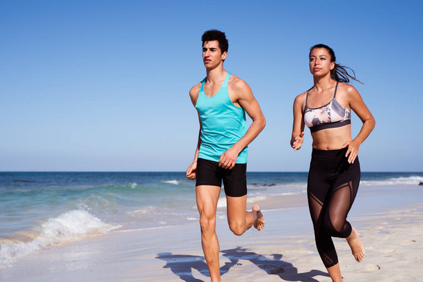 Man and woman jogging along the sea shore on a white sandy beach - Photo, Image