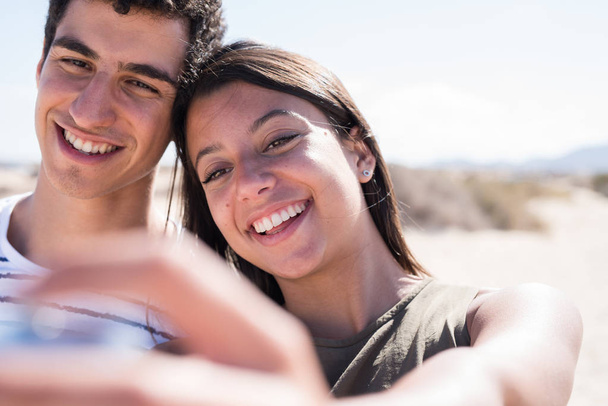 Close up of a young millennial couple smiling at the camera in a summer day - Foto, Imagen