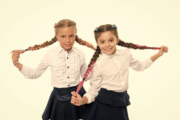Schoolgirls wear formal school uniform. Sisters little girls with braids ready for school. School fashion concept. Be bright. School friendship. Sisterhood relationship and soulmates. On same wave - Foto, afbeelding