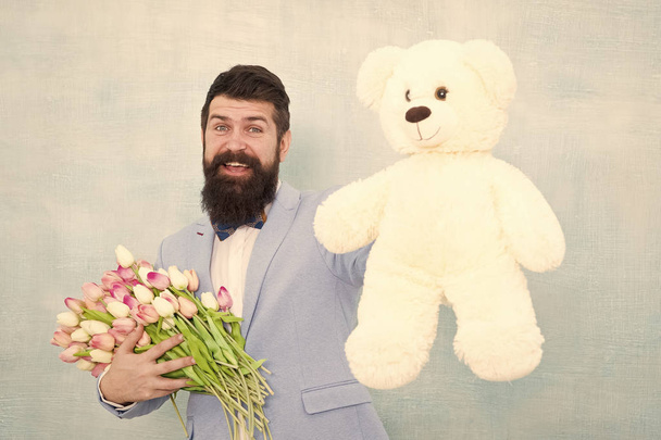 womens day. Formal businessman with teddy bear toy. spring bouquet. 8 of march. bride groom at wedding party. bearded man in bow tie with tulip flowers. love date with flowers. Happy Birthday - Foto, imagen