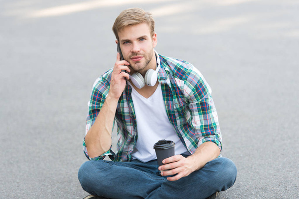 important call. phone call. listen music. ebook concept. man checkered shirt. student relax and recharge. coffee to go. guy drink coffee outdoor. man sit on ground. carefree student in headset - Φωτογραφία, εικόνα