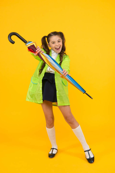 In case it will rain. Happy small schoolchild in raincoat holding umbrella against rain. Cute little girl with fashion accessory keeping her dry in wet rain weather. Its great for rain shower. - Zdjęcie, obraz
