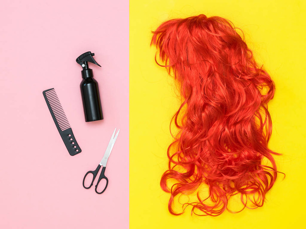 leuchtend orangefarbene Perücke und Haarstyling-Accessoires auf farbigem Hintergrund. Accessoires für Stil. - Foto, Bild