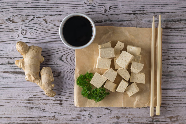 Tofu-juustoa, soijakastiketta, inkiväärijuurta ja puutikkuja. Soijajuustoa. Litteä
. - Valokuva, kuva