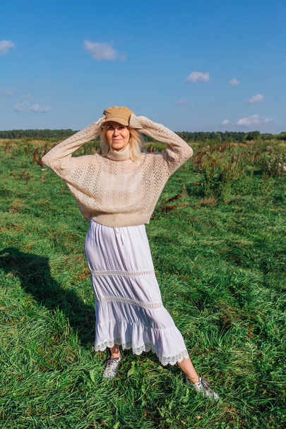 Happy beautiful blond woman walking in a green field - Photo, Image
