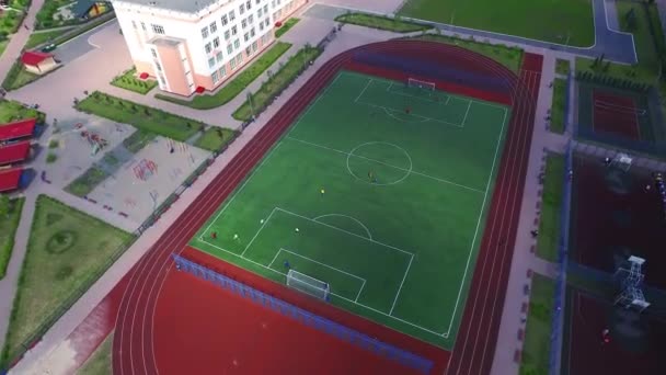 Εναέρια θέα ποδοσφαιριστές παίζοντας ποδόσφαιρο σε πράσινο χωράφι στην αυλή του σχολείου - Πλάνα, βίντεο