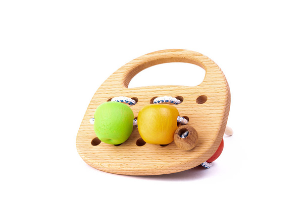 Foto van een houten houten speelgoed met kant en kralen van verschillende kleuren op de wielen van beuken. Speelgoed gemaakt van hout op een witte geïsoleerde achtergrond. Een speeltje voor het vermaken van kinderen en rust ouders - Foto, afbeelding