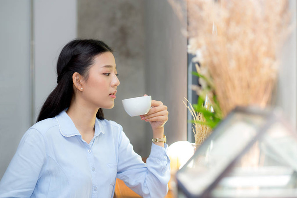 Kaunis nuori aasialainen nainen juo kahvia ja hymyilee mo
 - Valokuva, kuva