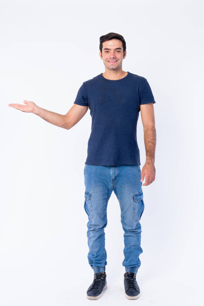 Full body shot of happy young Persian man showing something - Photo, Image