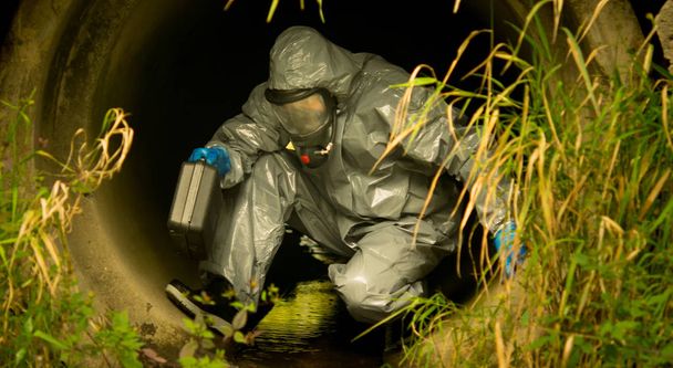scientist in protective clothing, with a suitcase comes into the drain pipe, to take samples, close-up - Photo, Image