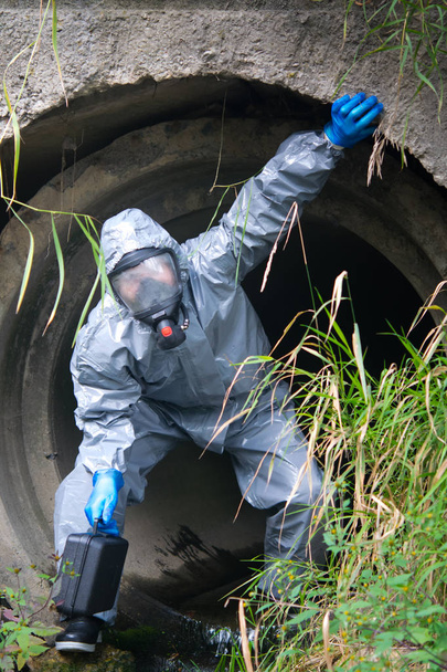 scientist in protective clothing, with a suitcase out of the drain pipe, which took a sample for testing - Valokuva, kuva