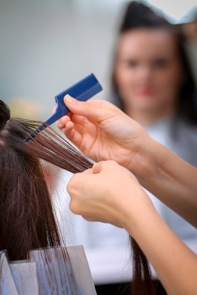 Girl in beauty salon while an hair stylist dyeing her hair - Fotó, kép