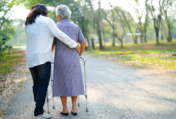Ayuda y cuidado Asiático senior o anciana anciana señora uso caminante con fuerte salud mientras camina en el parque en feliz vacaciones frescas. - Foto, Imagen