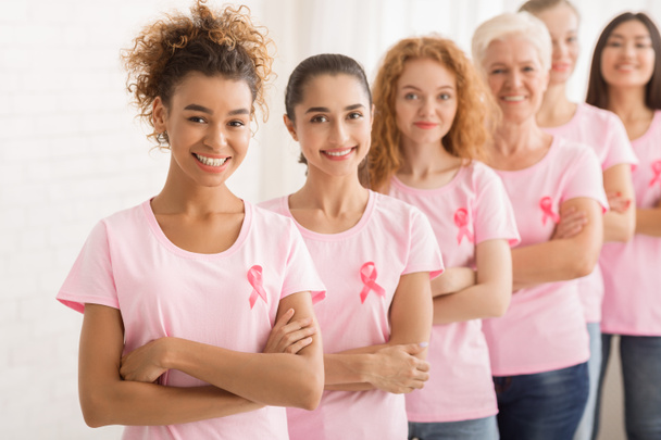 Жіночий добровольців в рак молочної залози футболки стоячи над білою стіною - Фото, зображення