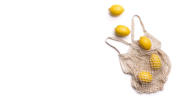 Літаючі свіжі лимони поза екологічною сумкою на білому тлі
 - Фото, зображення