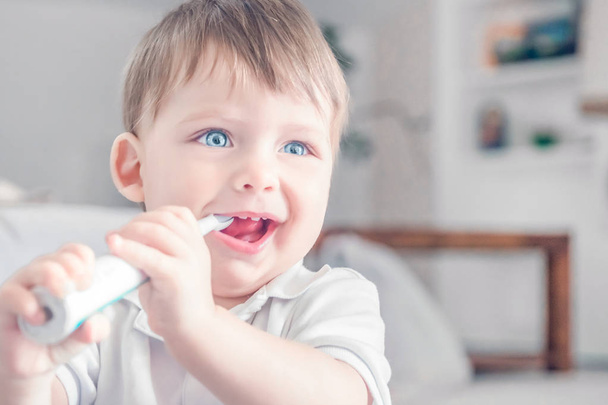 Smiling little boy brushing his teeth in the room. - Foto, afbeelding