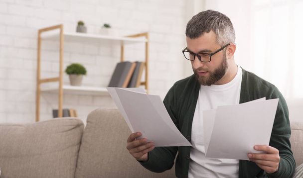Businessman doing work at home, reading documents - Фото, изображение