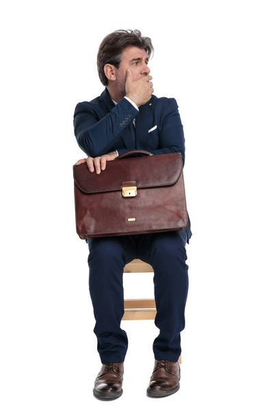 бизнесмен сидит с портфелем на коленях держа руку над факсом
 - Фото, изображение