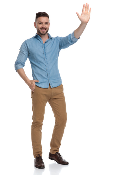 hombre casual de pie con una mano en el bolsillo y saludando
 - Foto, imagen