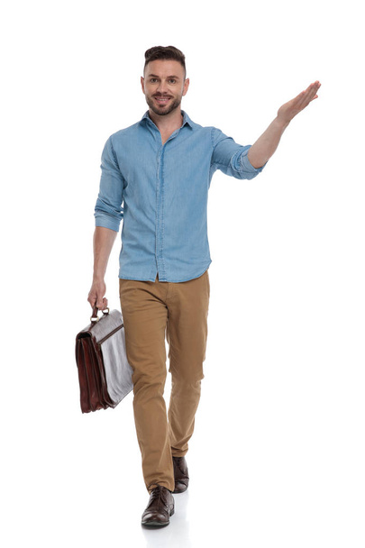 casual man with briefcase walking and presenting happy - Foto, Bild