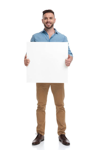 casual man standing with billboard on hands happy - Photo, Image