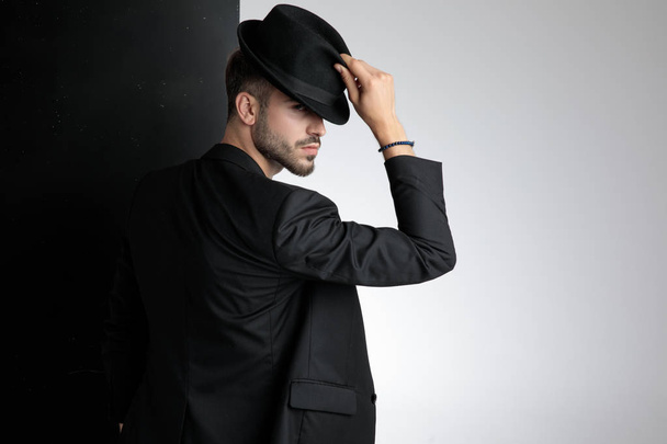 polite young man holding black hat in studio - Foto, imagen