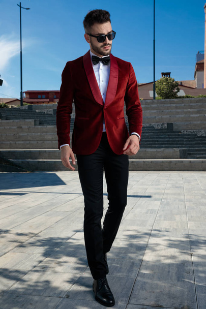 büszke fiatal elegáns férfi séta piros bársony szmoking - Fotó, kép