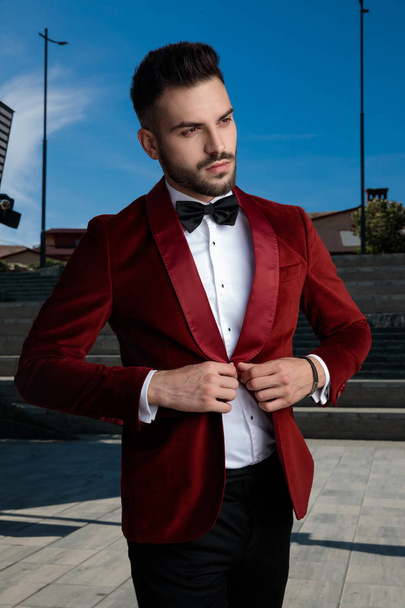 concerned young elegant man arranging coat outside - Fotografie, Obrázek