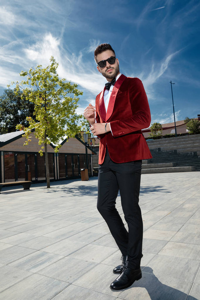 arrogante jovem elegante homem ajustando manga ao ar livre
 - Foto, Imagem