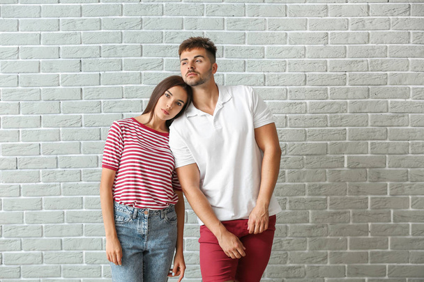 Fashionable young couple against brick wall - Photo, Image