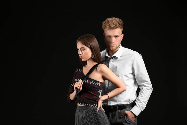 Portrait of fashionable young couple on dark background - Photo, Image