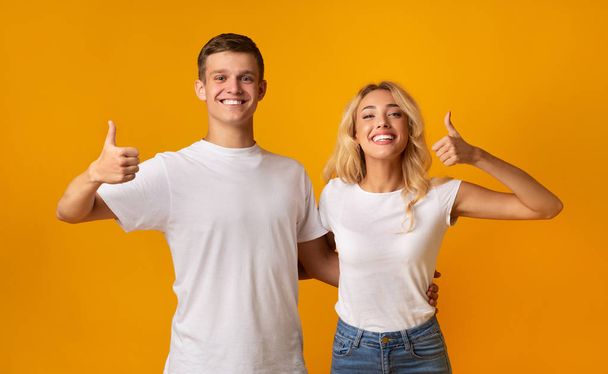 Šťastný pár objevil palce nad žlutým pozadím - Fotografie, Obrázek