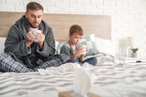 Father and his little son ill with flu at home - Foto, Bild