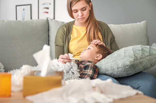 Frau misst Temperatur ihres kranken Sohnes zu Hause - Foto, Bild