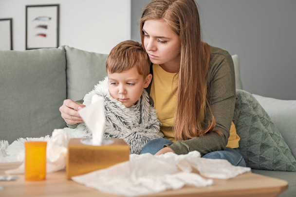 Mujer midiendo la temperatura de su hijo enfermo en casa
 - Foto, Imagen