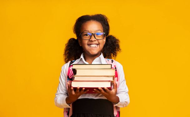 Μαθήτρια κρατώντας στοίβα των βιβλίων χαμογελά στην κάμερα, στούντιο shot - Φωτογραφία, εικόνα