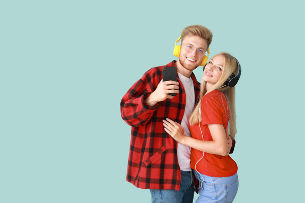 Young couple listening to music on color background - Photo, image