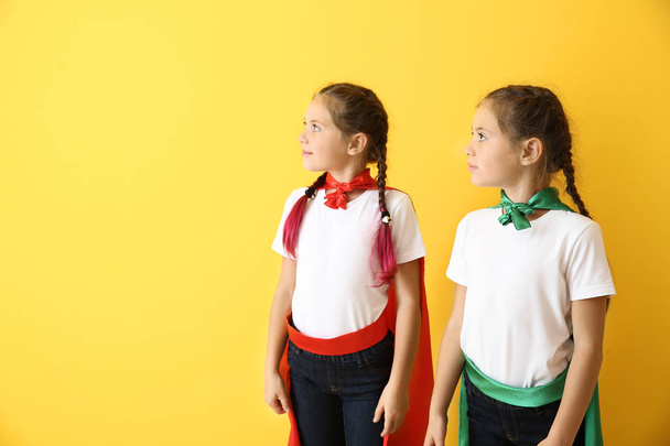 Portret bliźniaczych dziewczynek przebranych za superbohaterów na kolorowym tle - Zdjęcie, obraz