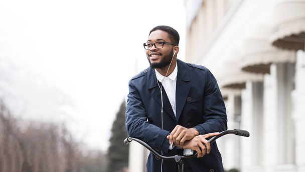 Afro uomo d'affari in bicicletta per andare al lavoro e ascoltare musica
 - Foto, immagini