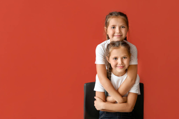 Portrait of cute twin girls on color background - Foto, afbeelding