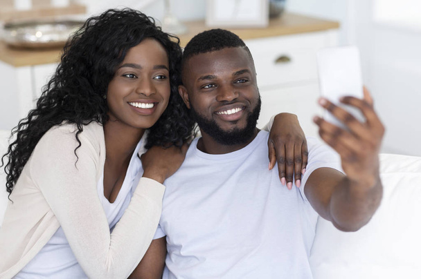 Happy black couple taking selfie with smartphone at home - Фото, зображення