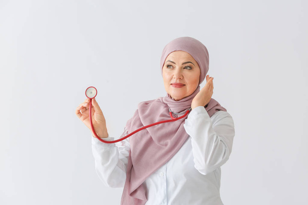 Kaunis kypsä muslimi lääkäri stetoskoopilla valolla taustalla
 - Valokuva, kuva