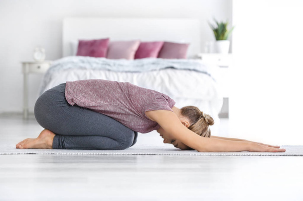 Jonge vrouw beoefenen van yoga in de slaapkamer - Foto, afbeelding