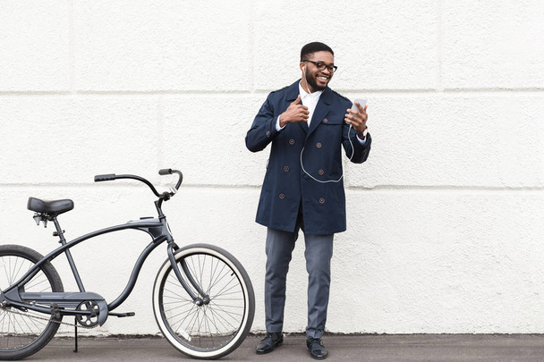 Szczęśliwy człowiek co rozmowy wideo na telefon w pobliżu roweru - Zdjęcie, obraz