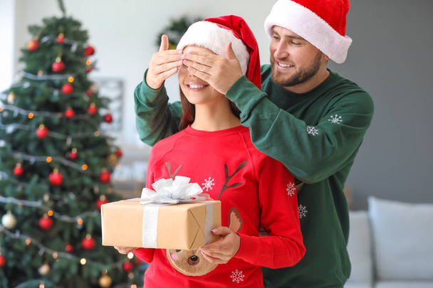 Un homme fait un cadeau à sa femme la veille de Noël
 - Photo, image