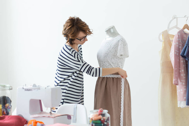 Fashion designer, seamstress and Small-Sized Enterprises concept - woman seamstress decorates a mannequin - Fotó, kép