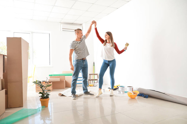 Joyeux jeune couple dansant tout en faisant des réparations dans leur nouvelle maison
 - Photo, image
