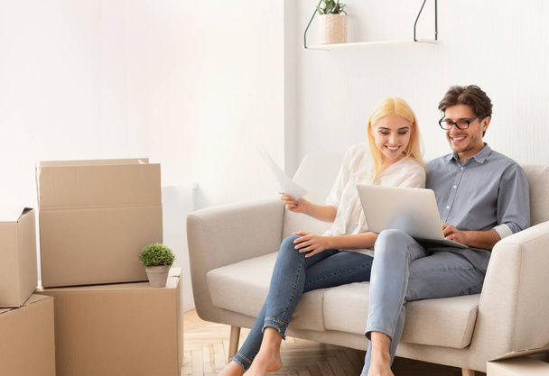 Sposi che navigano sul computer portatile seduto sul divano in nuovo appartamento
 - Foto, immagini
