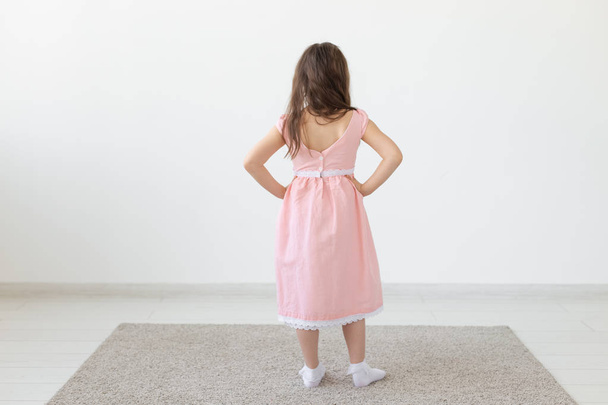 ファッションデザイナー、子供と子供のコンセプト - スタジオで服を着てポーズ小さな女の子のバックビュー - 写真・画像