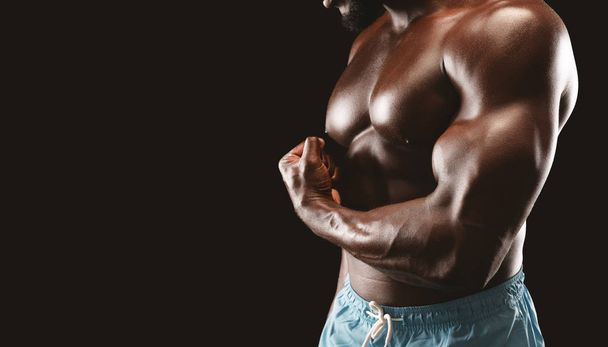 Cropped image of black bodybuilder demonstrating his arm strength - Zdjęcie, obraz